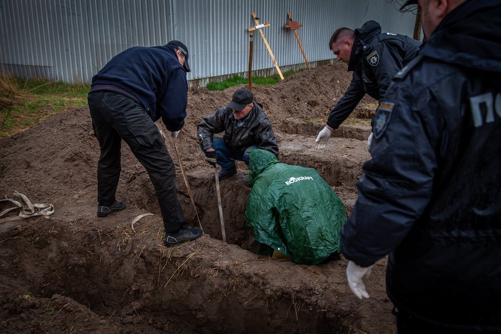 Gennadiy, a resident who buried his neighbours, helps to bring them up from their graves.