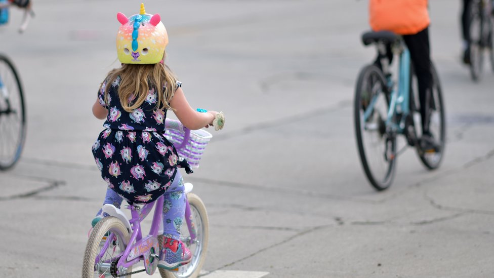 Ребенок едет на велосипеде за взрослым