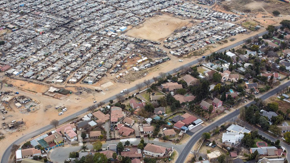 Una carretera divide el barrio de clase media de Bloubusrand, en Johannesburgo, del campo Kya Sands, hogar de muchos inmigrantes. Una carretera divide el barrio de clase media de Bloubusrand, en Johannesburgo, del campo Kya Sands, hogar de muchos inmigrantes.