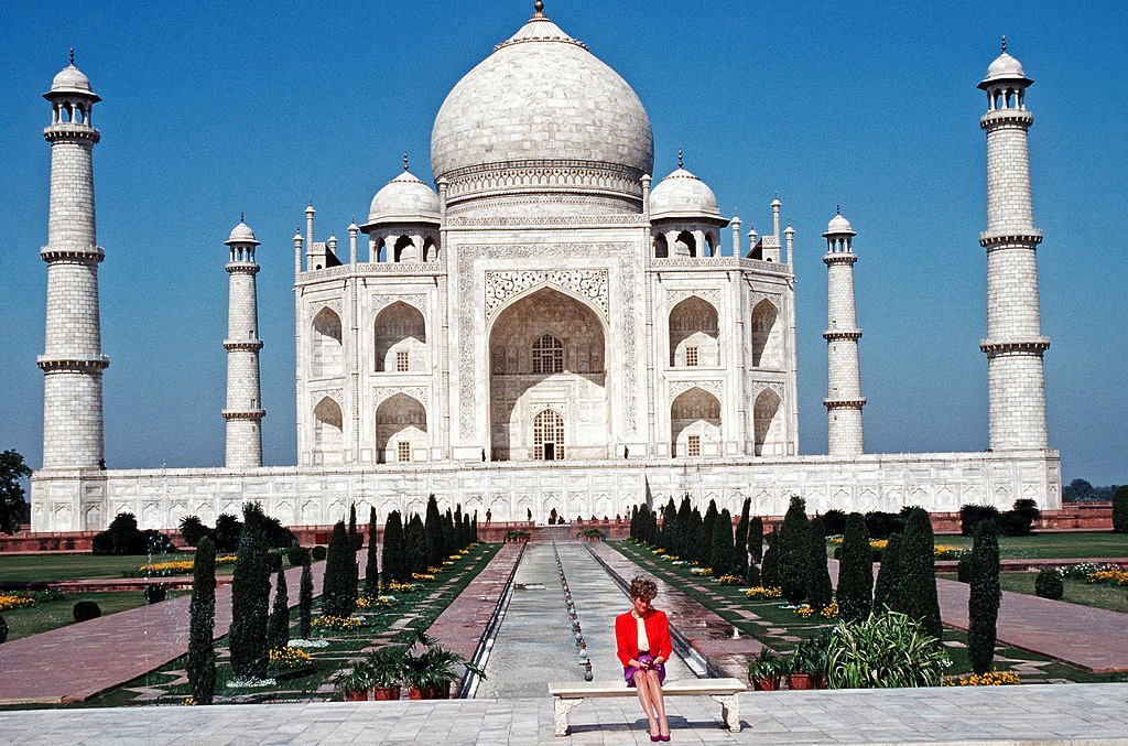 Diana, Princess of Wales, wearing a red and purple suit designed by Catherine Walker, poses alone outside the Taj Mahal on February 11, 1992 in Agra, India.