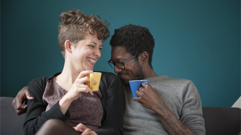Homem e mulher rindo tomando café juntos