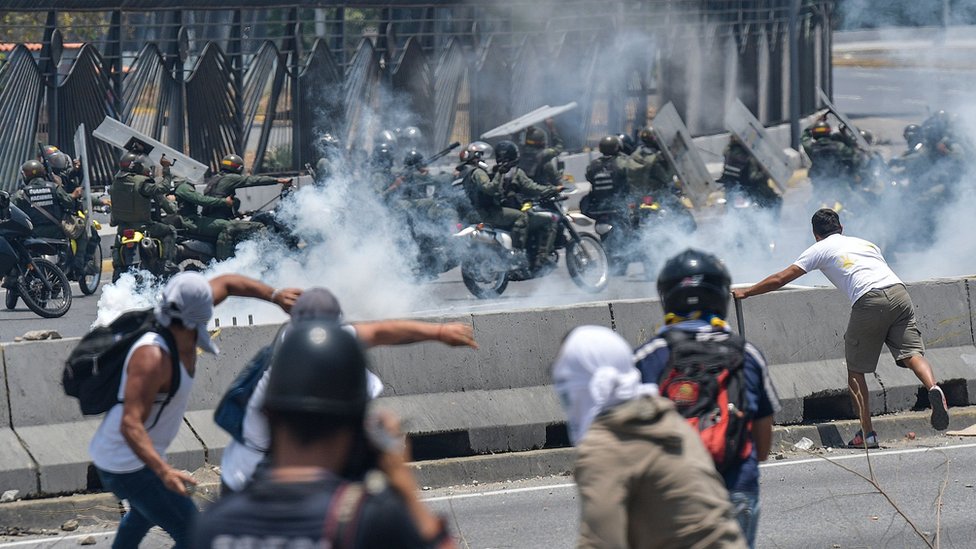 Manifestantes y fuerzas policiales enfrentándose en Caracas, Venezuela.