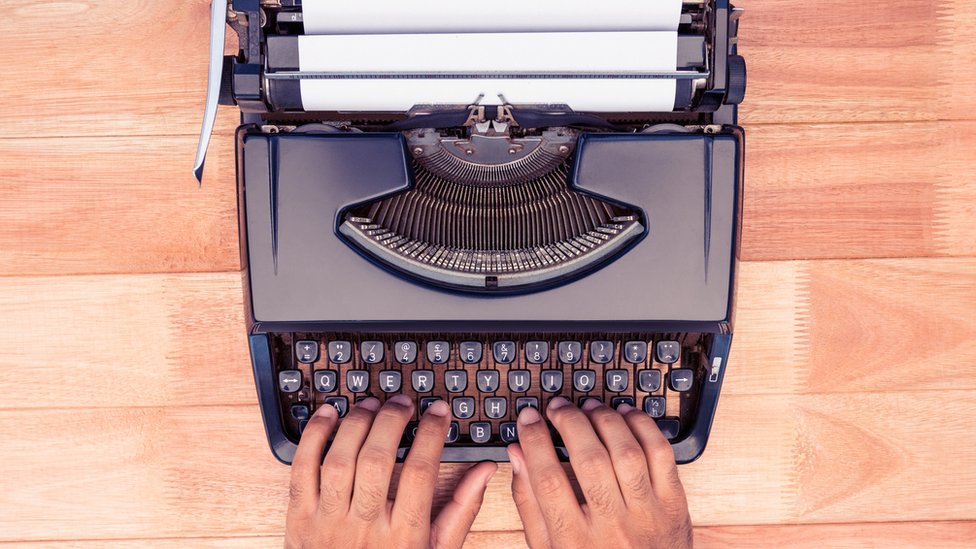 Máquina de escribir antigua con dos manos.