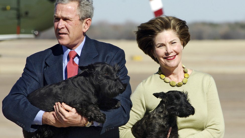 US President George W. Bush carries his dog Barney as Fist Lady Laura Bush holds Miss Beazley in 2005