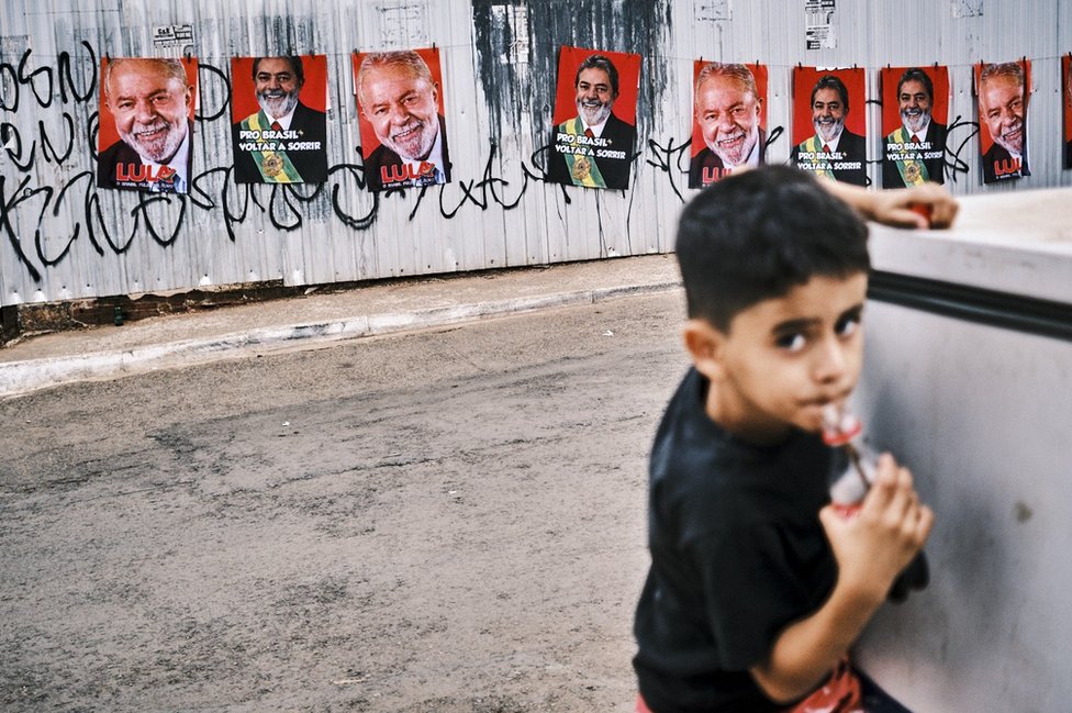 一個巴西兒童在街上喝可口可樂，後面是盧拉的競選畫報