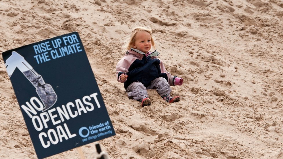 Маленький ребенок с плакатом против угольной шахты