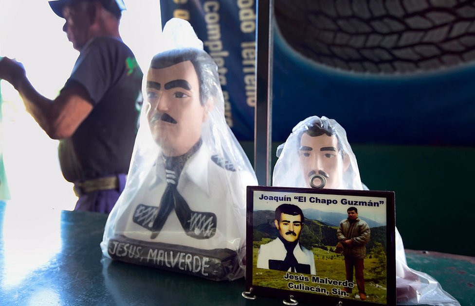 Tras ser extraditado a EE.UU. en enero, "El Chapo" enfrenta ahora un juicio en una corte federal de Nueva York. Una foto de Joaquín "el Chapo" Guzmán frente a dos figuras de Malverde en una tienda contigua a una capilla dedicada al santo en Culiacán, Sinaloa, México, el 7 de diciembre de 2016.