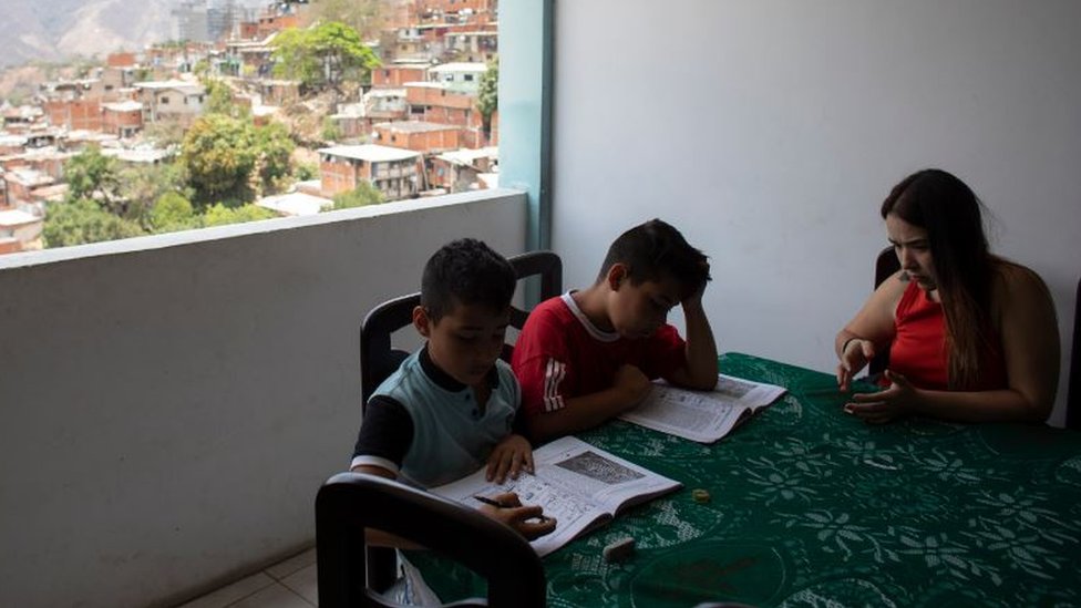 أم تساعد طفليها في الدراسة بأحد الأحياء الفقيرة في العاصمة الفنزويلية كراكاس