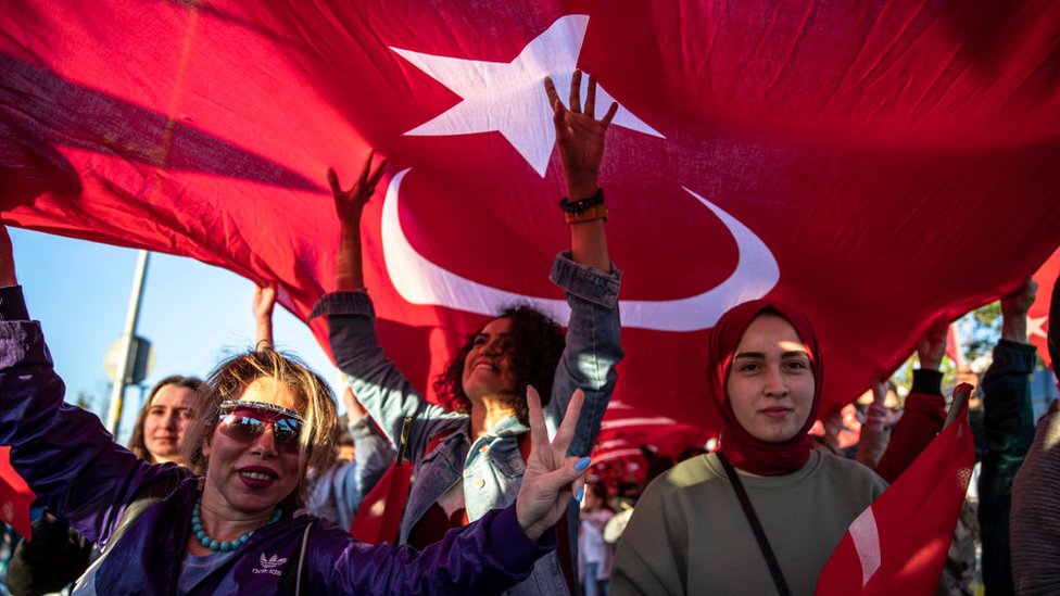Mujeres debajo de una bandera gigante turca.