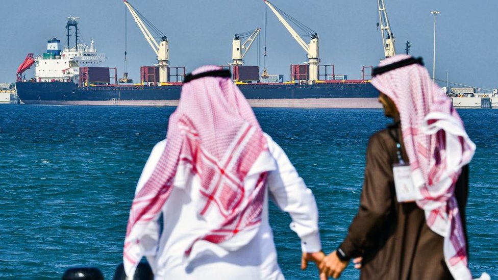 Двое мужчин в Саудовской Аравии стоят перед нефтяным танкером