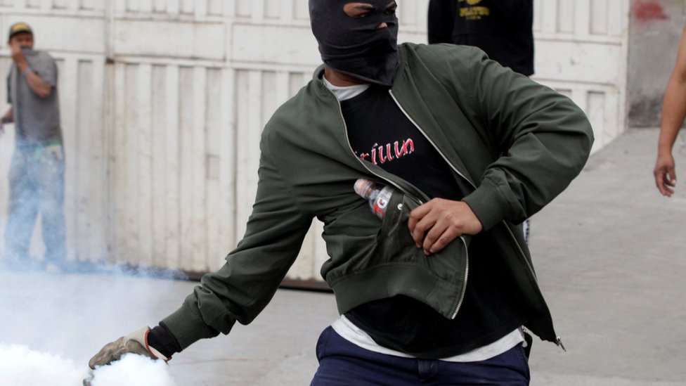 Демонстрант бросает баллончик со слезоточивым газом в полицию. , во время акции протеста против переизбрания президента Гондураса Хуана Орландо Эрнандеса в Тегусигальпе, Гондурас, 20 января 2018 г.