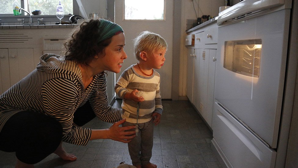 woman and child look at oven