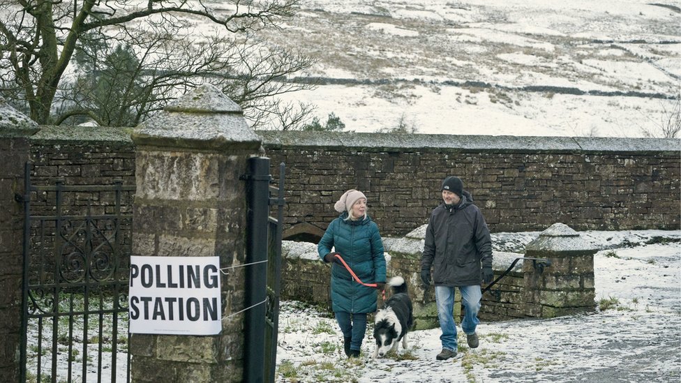 Пара и собака на избирательном участке в снегу