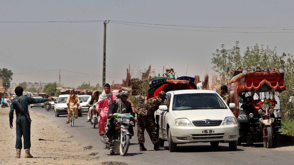 Afghan police search commuters at a checkpoint during a period of fighting in 2016