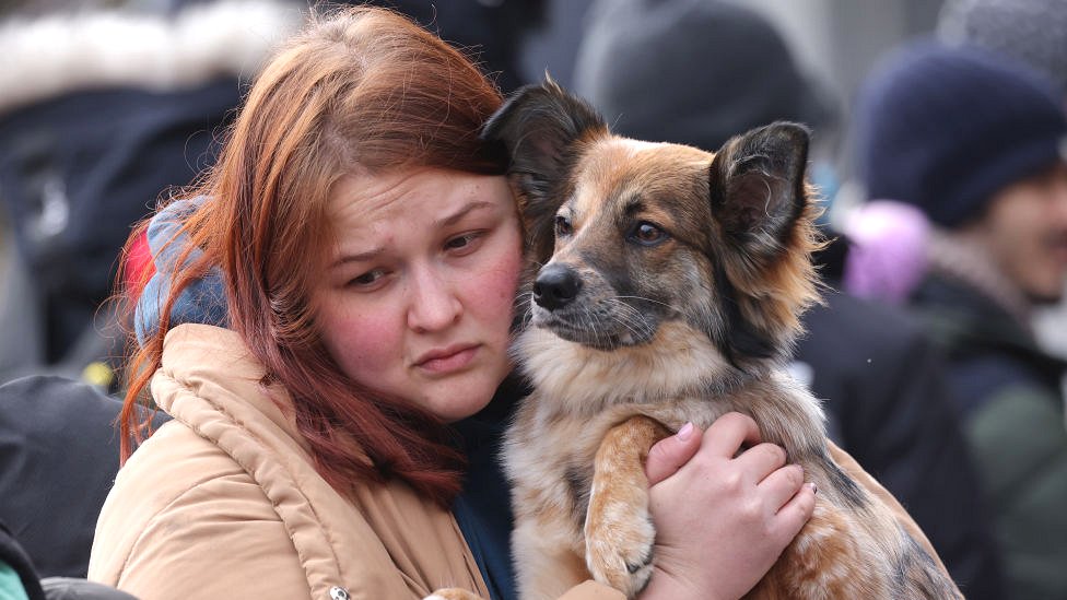 Jovem abraça seu cachorro enquanto eles aguardam para cruzar a fronteira entre a Ucrânia e a Polônia