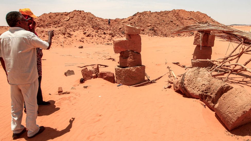 Махмуд ат-Тайеб, бывший эксперт отдела древностей Судана, осматривает камни, сложенные друг на друга, чтобы подпереть крышу столовой, которую используют охотники за золотом