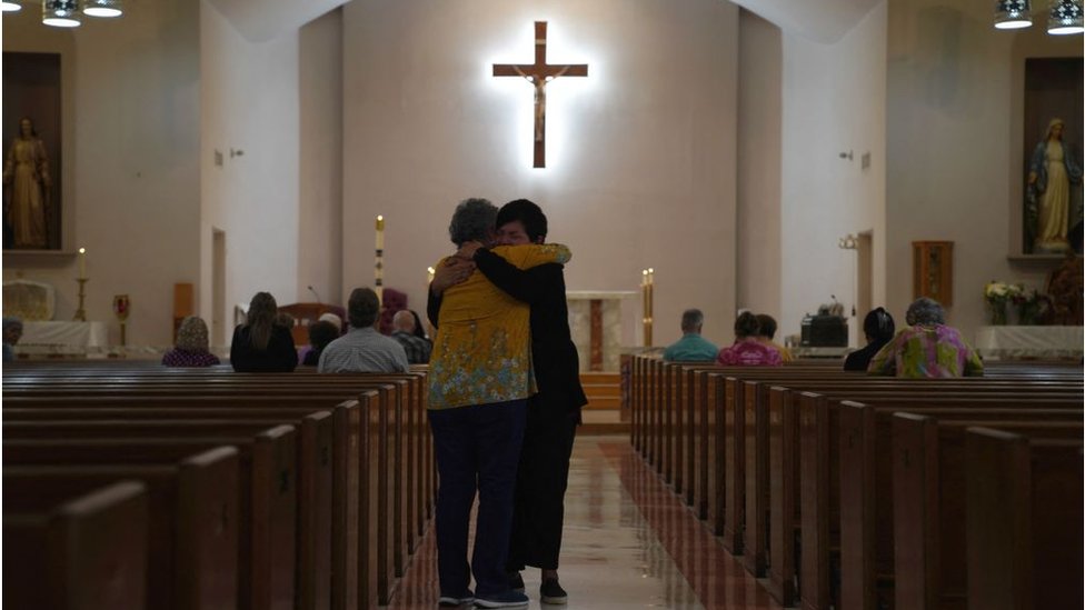 Dos mujeres se abrazan en una iglesia católica en Uvalde.