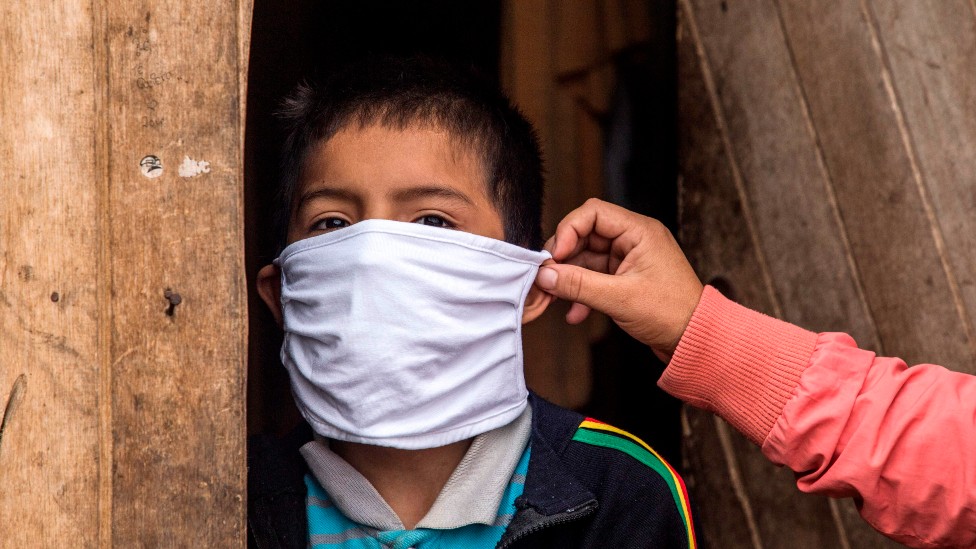 Mãe coloca máscara no filho no Peru