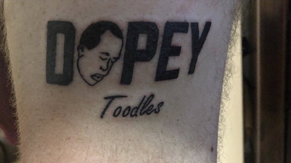 Татуировка с логотипом Dopey со словом «toodles» на руке неизвестного