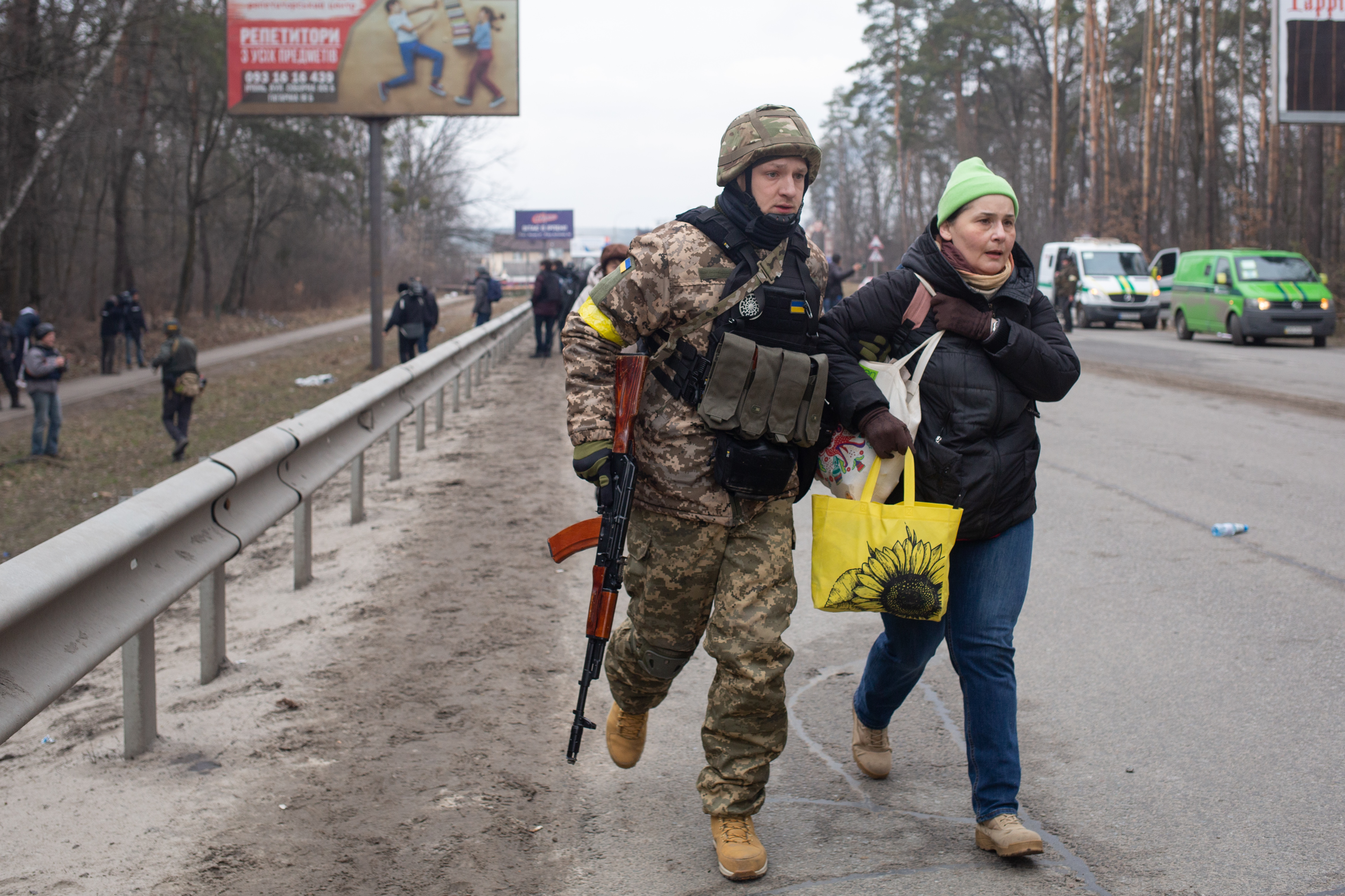 A Ukrainian soldier helps a civilian woman in Kyiv