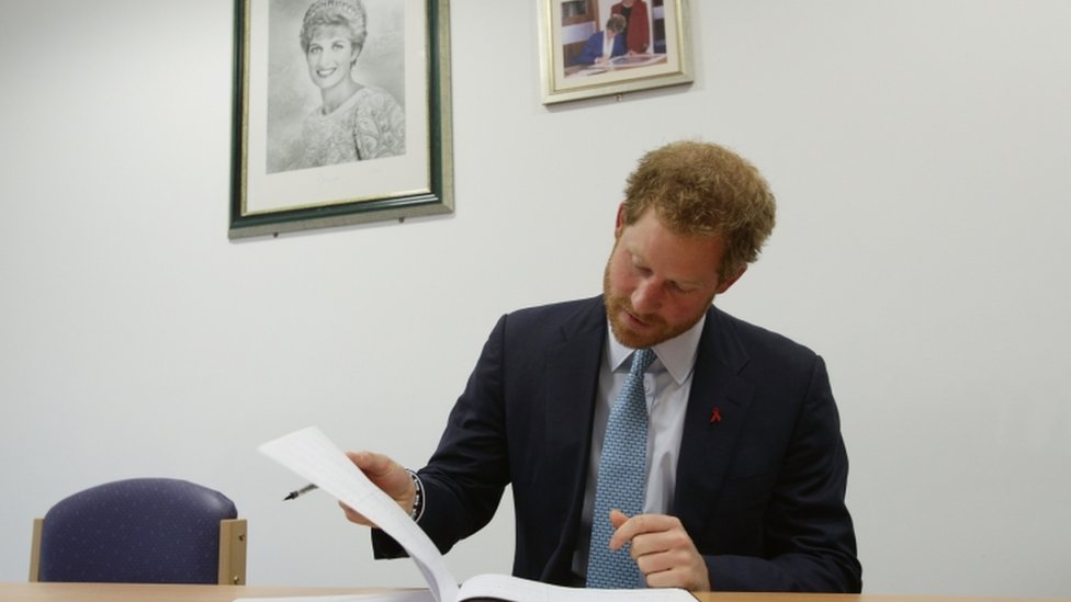Принц Гарри подписывает книгу посетителей