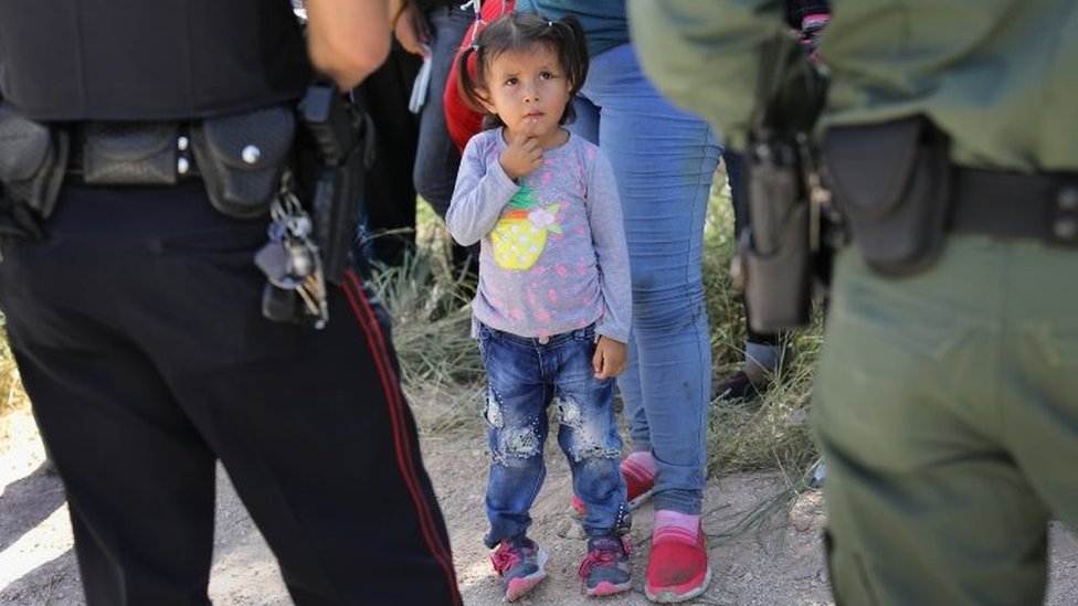 Una niña junto a agentes fronterizos