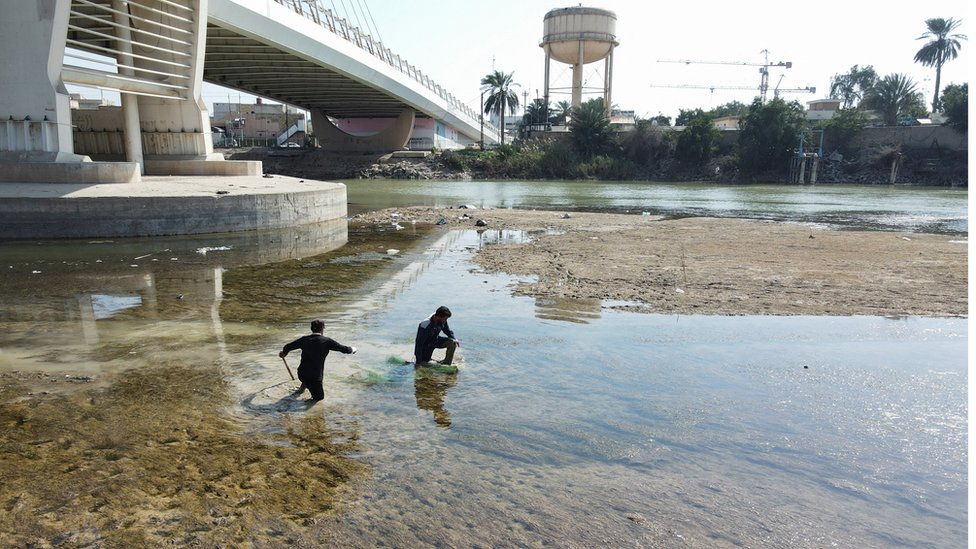 صيادون عراقيون يمشون في نهر دجلة حيث يشهد انخفاضاً حاداً في منسوب المياه في العمارة