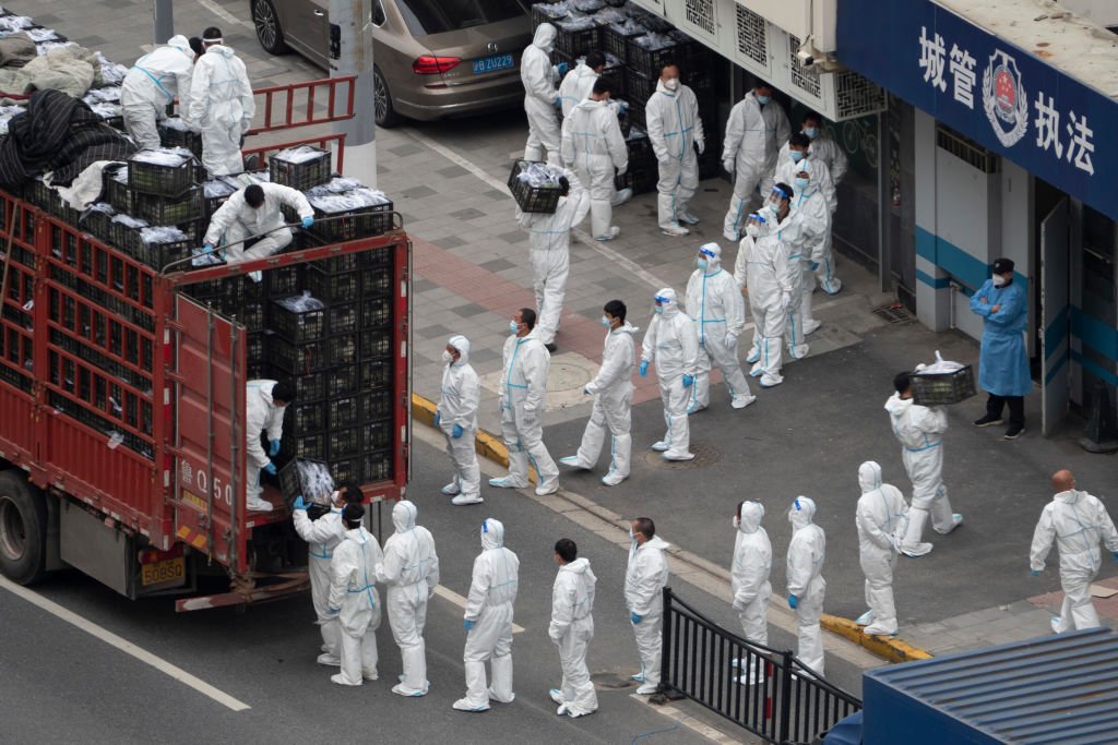 Workers in protective suits unload supplies in Shanghai