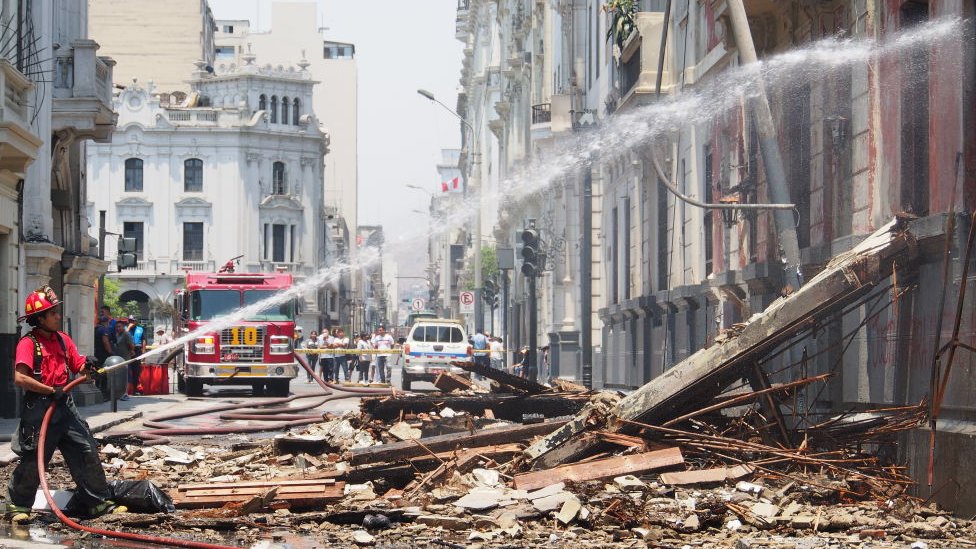 Un bombero lanza agua a un edificio incendiado en el centro de Lima.