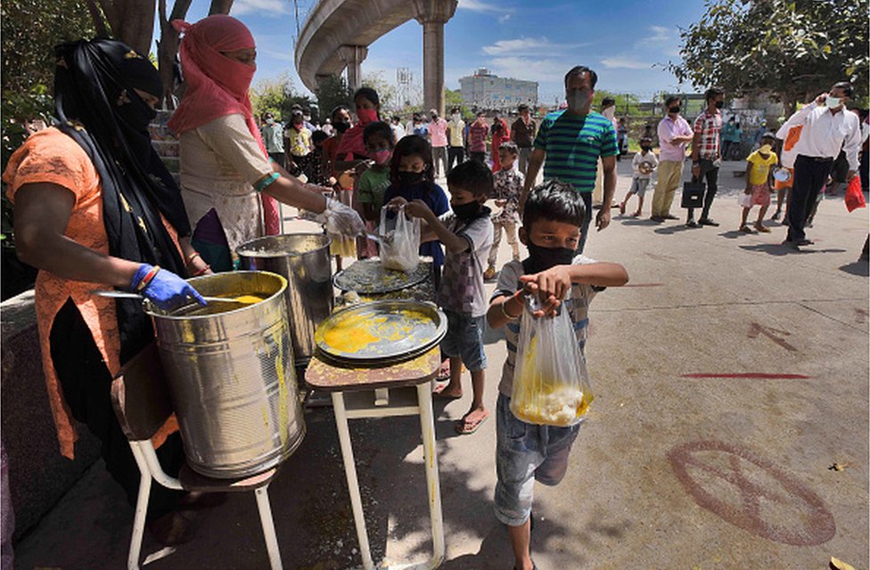 Уличные дети получают еду от благотворительной организации в Дели во время карантина из-за коронавируса