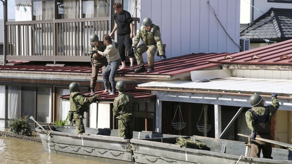 Японские солдаты используют лодки, чтобы помочь людям во время сильных наводнений