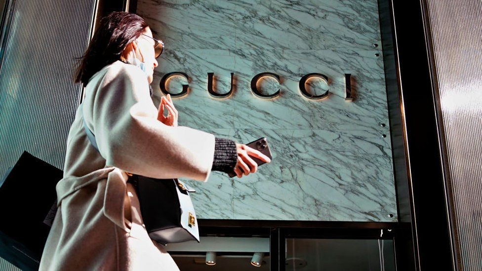 Mujer entrando con el celular en la mano a una tienda de Gucci