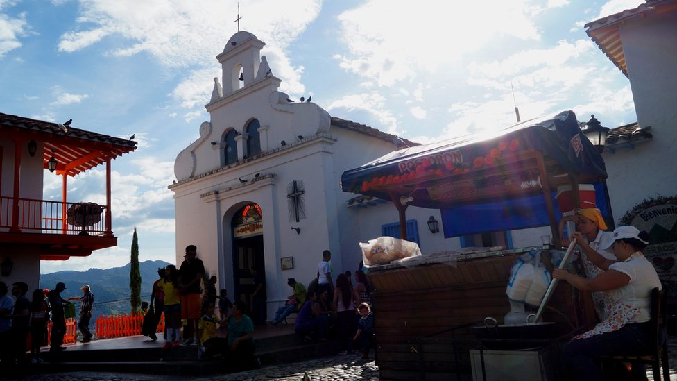 Mujeres revolviendo una paila junto a un toldo azul Mujeres revolviendo una paila junto a un toldo azul