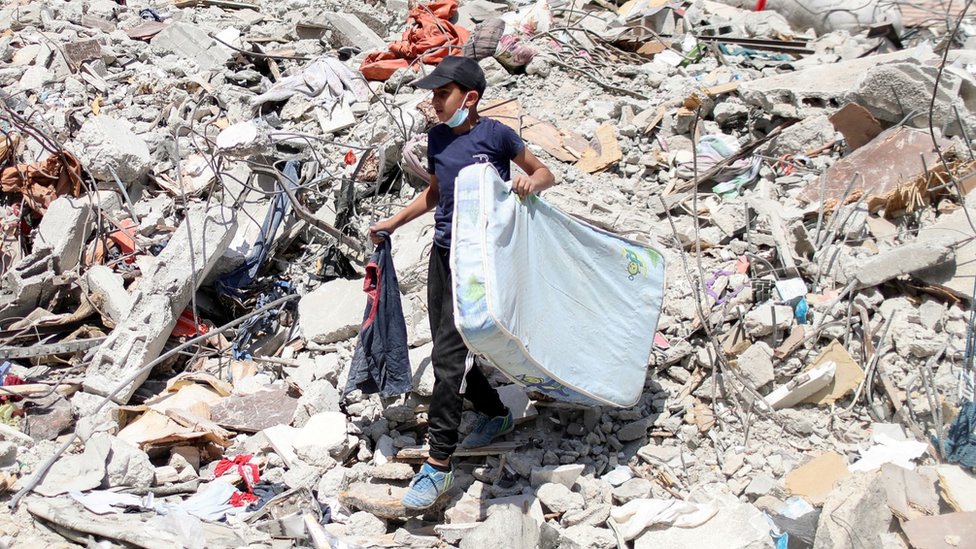 Seorang bocah Palestina membersihkan puing-puing