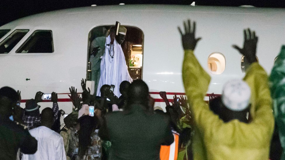 Бывший президент Яя Джамме (C, вверху), лидер Гамбии в течение 22 лет, машет рукой из самолета, покидая страну 21 января 2017 года в Банжуле