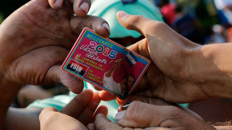 Antiguos simpatizantes sandinistas tratan de quemar su carnet de militantes del FSLN.