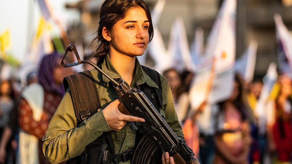 Сотрудник сирийских курдских сил внутренней безопасности стоит на страже, когда курды протестуют в Касмишли против турецких угроз начать наступление на север Сирии (27 августа 2019 г.)