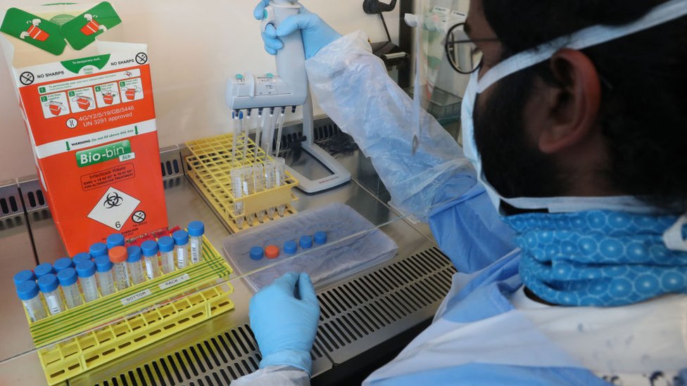 Технические специалисты осуществляют перенос образцов во время открытия нового центра тестирования Covid-19 лаборатория в больнице Университета Королевы Елизаветы