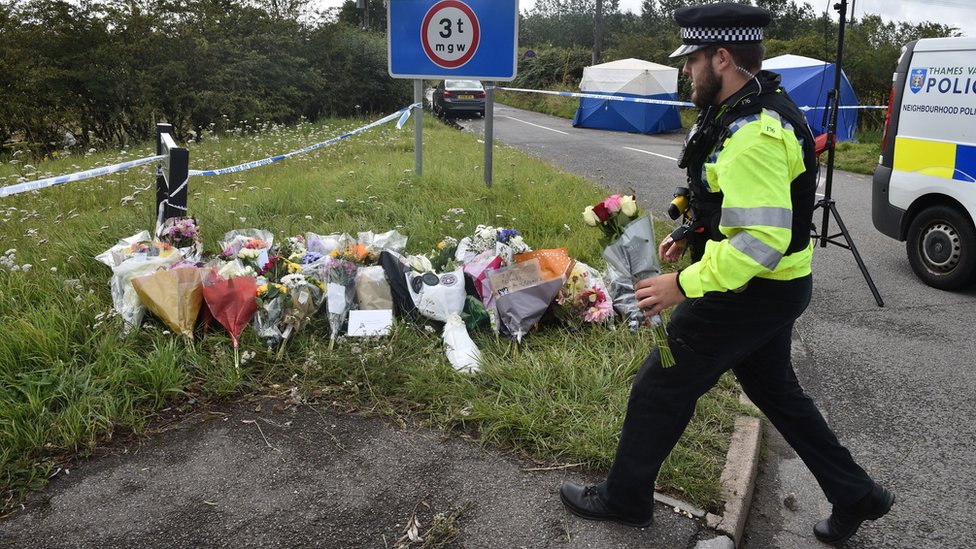 Полицейский возлагает цветы на месте убийства констебля Эндрю Харпера