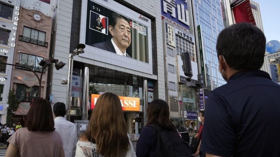 People watch a television announcement on Abe`s resignation