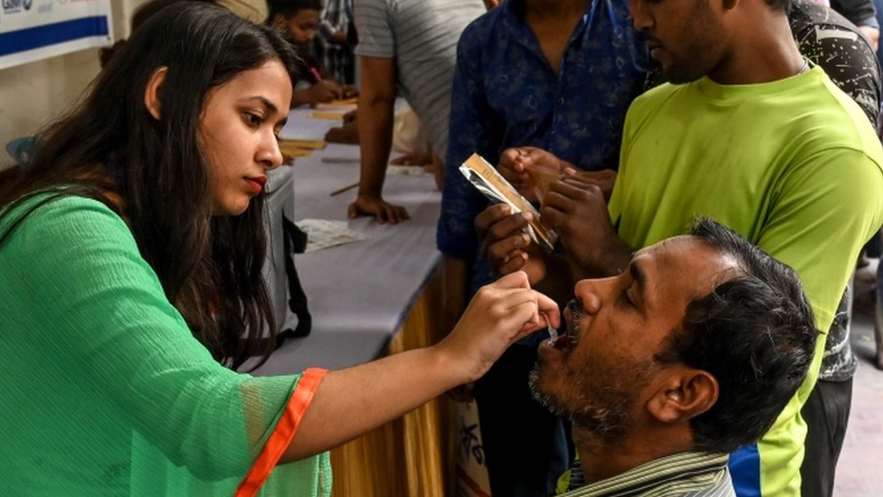 Un hombre recibe una vacuna por vía oral de una trabajadora de la salud en Daca, Bangladesh, febrero 2020