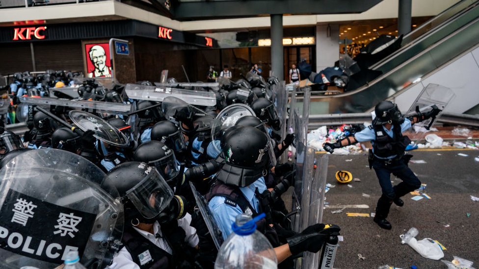 Полицейский бросает канистру со слезоточивым газом во время акции протеста 12 июня 2019 года в Гонконге, Китай.