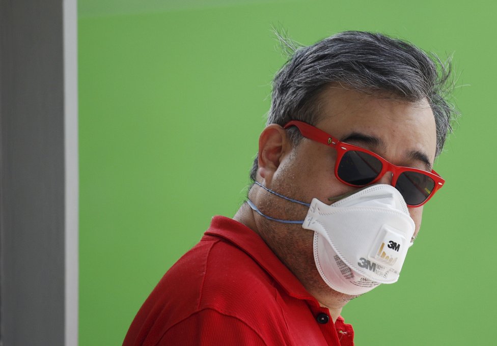 Мужчина в маске для защиты от тумана ждет на избирательном участке во время всеобщих выборов в Сингапуре 11 сентября 2015 года.