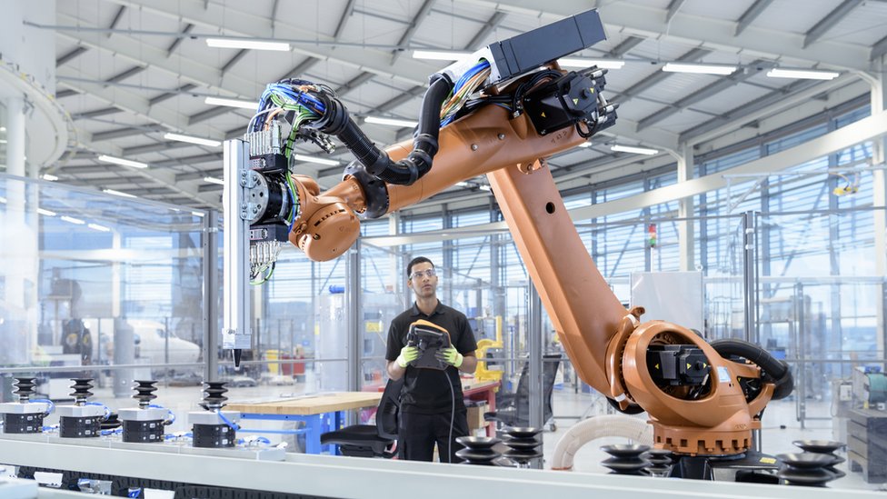 radnik kontroliše robota u proizvodnji