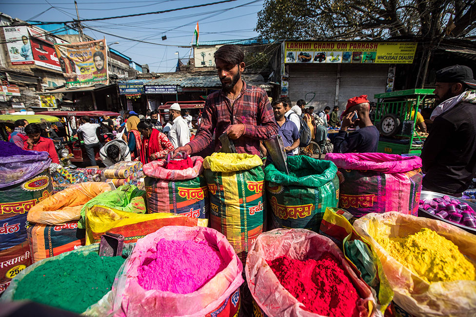 بائع يبيع مسحوقًا ملونًا للمهرجان الهندوسي القادم هولي، في سوق سادار بازار في الأحياء القديمة في نيودلهي.