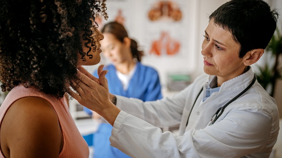 Doctora inspecciona el cuello de una mujer