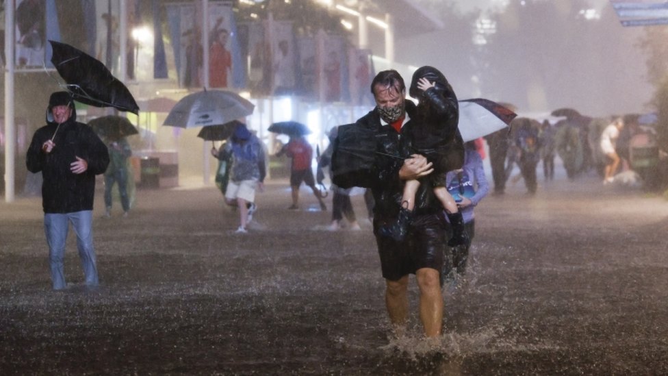 أشخاص يمشون تحت أمطار غزيرة