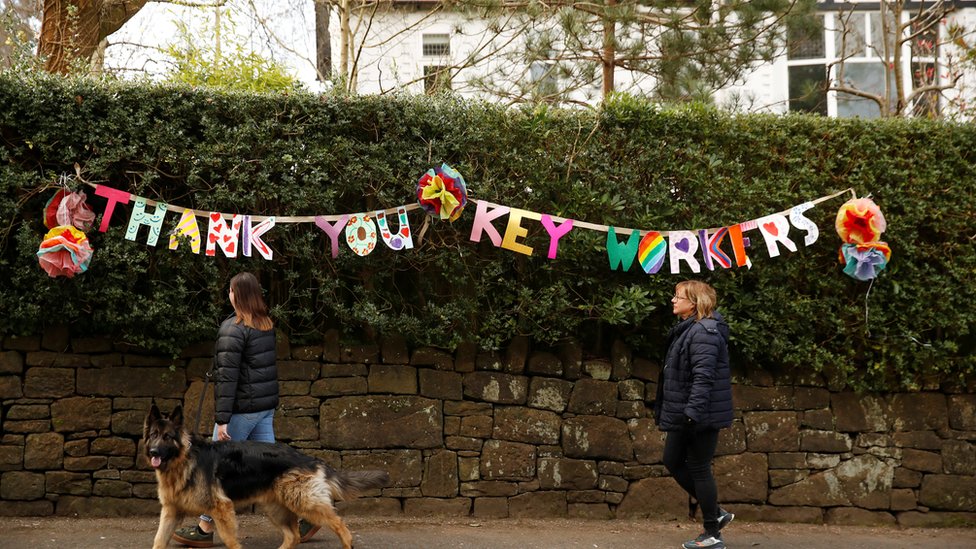Люди проходят мимо плаката с надписью« Спасибо, ключевые сотрудники », поскольку распространение коронавирусной болезни (COVID-19) продолжается, Манчестер