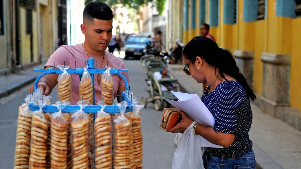 Una mujer compra rosquillas a un vendedor ambulante en La Habana.