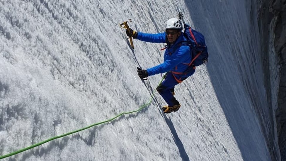 Эрик Верт поднимается на почти вертикальную горную вершину, полностью экипированный зубилом, веревками и шлемом.